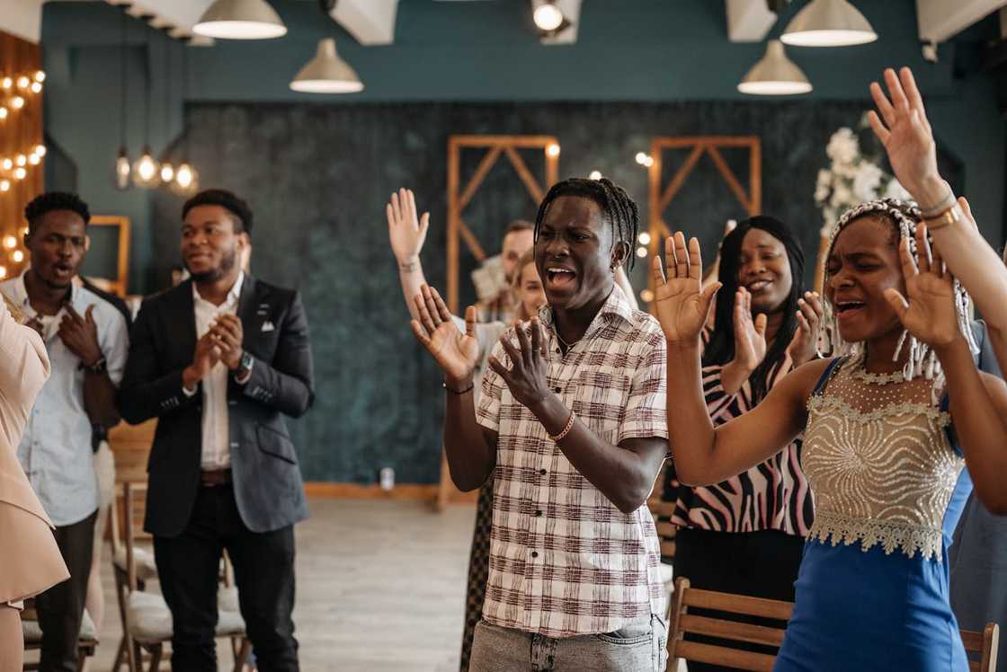 A group of people worshipping indoors, clapping and singing during a church service. A group of people worshipping indoors, clapping and singing during a church service.