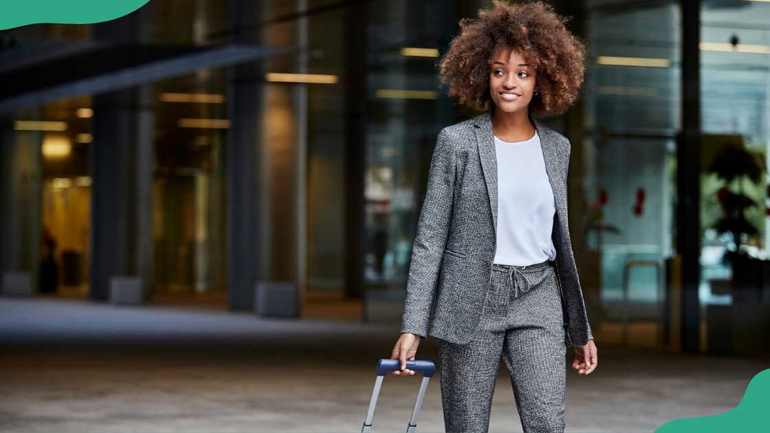 A young woman with luggage walking outside an office building A young woman with luggage walking outside an office building