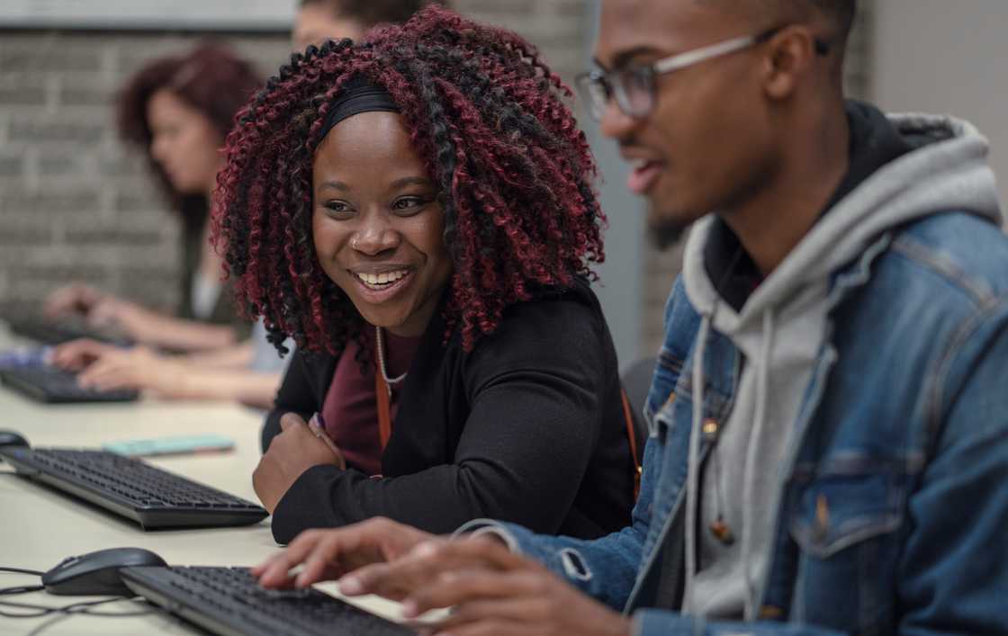University students type on a computer while working together on a university assignment. University students type on a computer while working together on a university assignment.