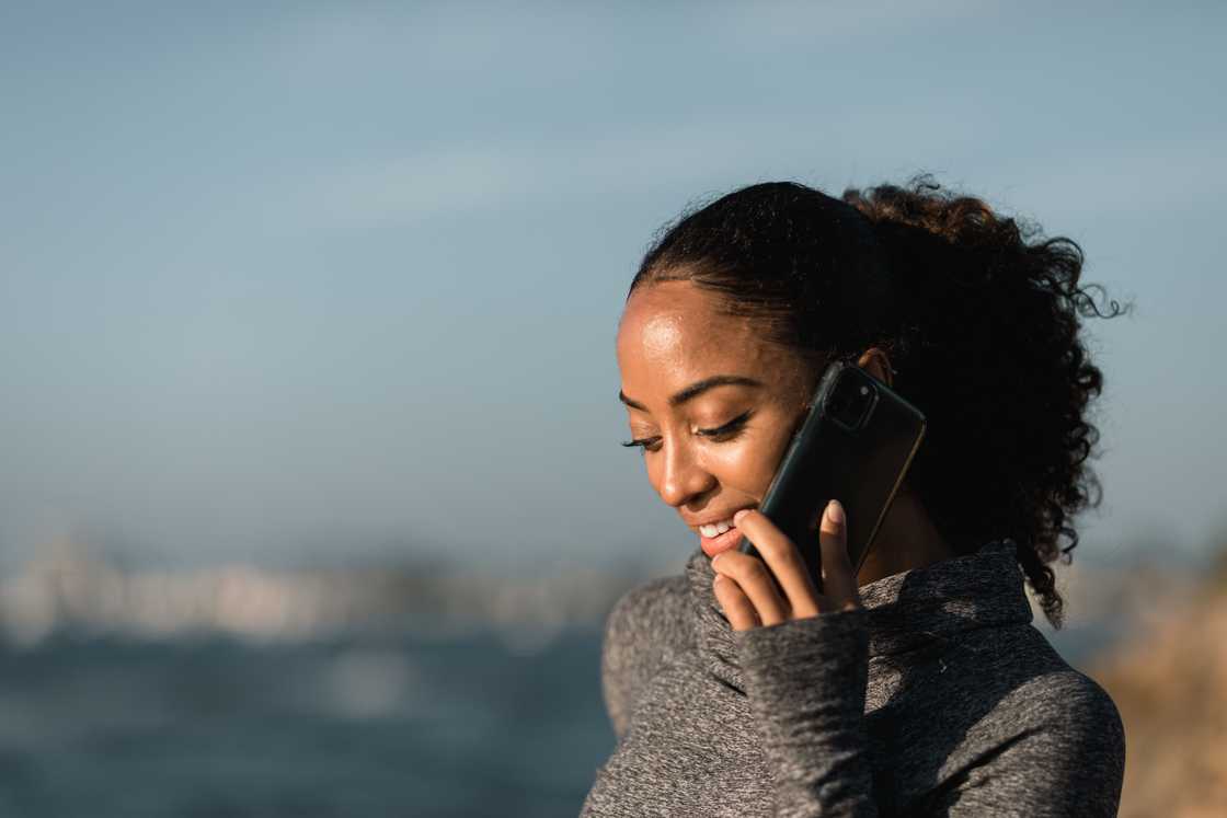 A woman in a grey sweater using a black smartphone