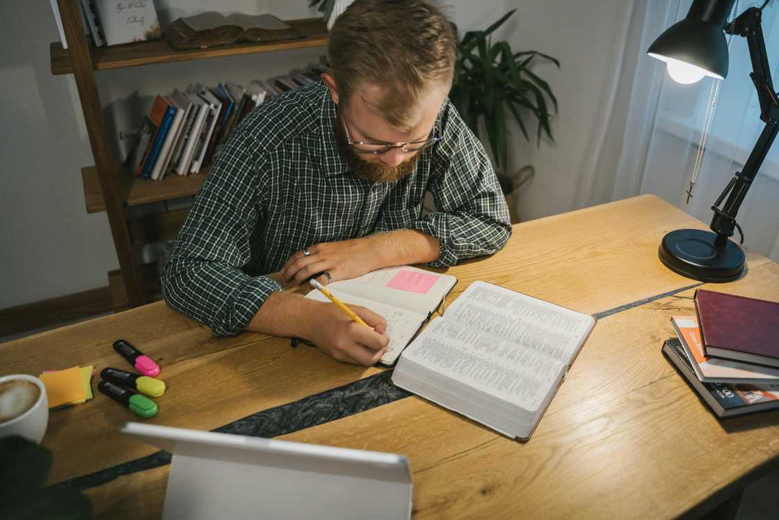 A man studying the Bible while taking notes