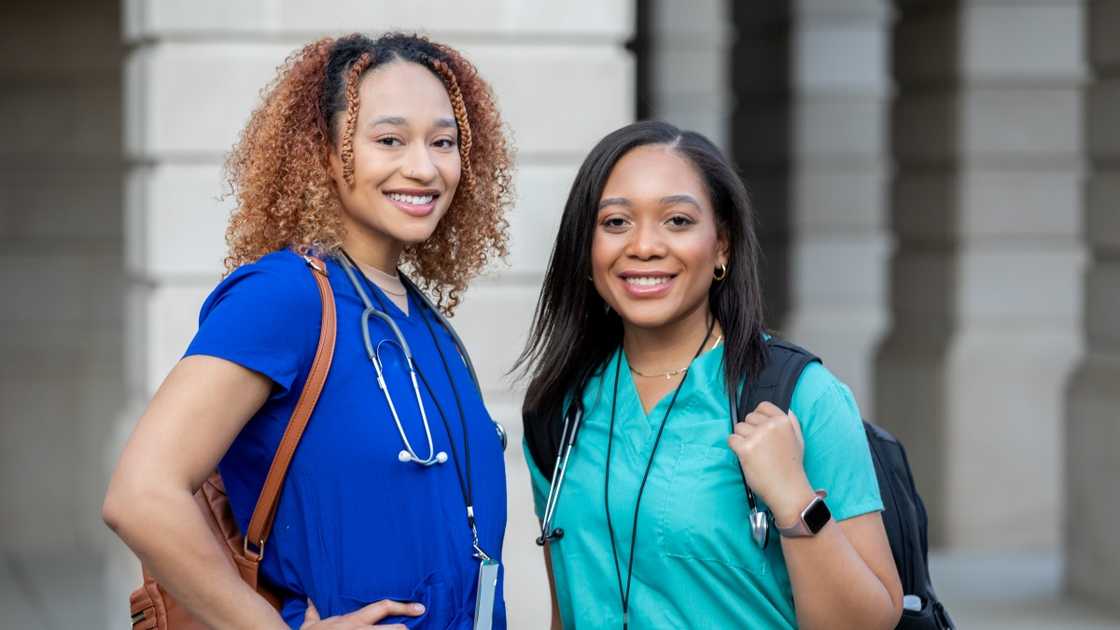 College students pose for a photo in blue and green scrubs.