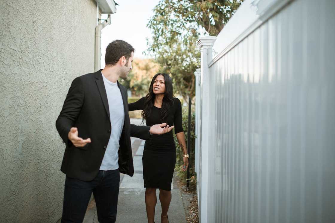 A man and woman argue while walking through a narrow outdoor passage. A man and woman argue while walking through a narrow outdoor passage.