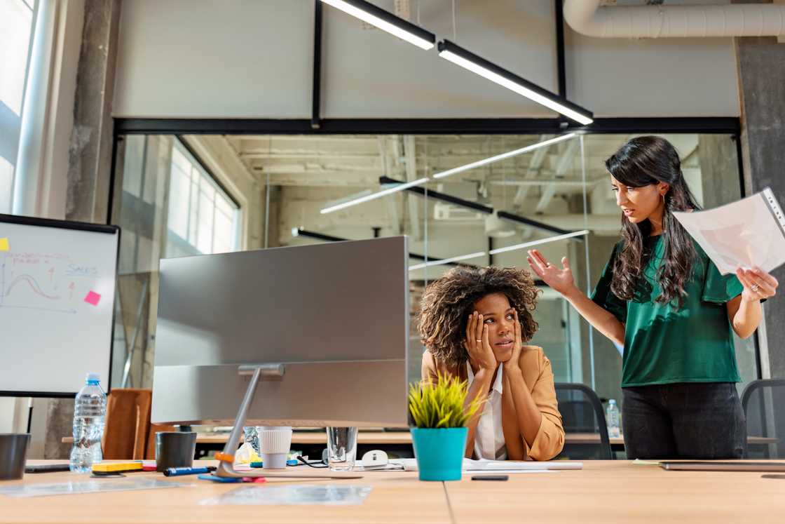 A businesswoman stands while arguing with a colleague A businesswoman stands while arguing with a colleague