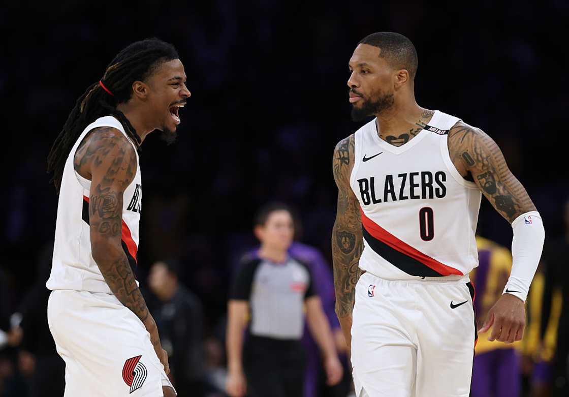 Ja Morant and Damian Lillard in white Trail Blazers jerseys celebrating on court during a win over the Lakers in Los Angeles, 2026