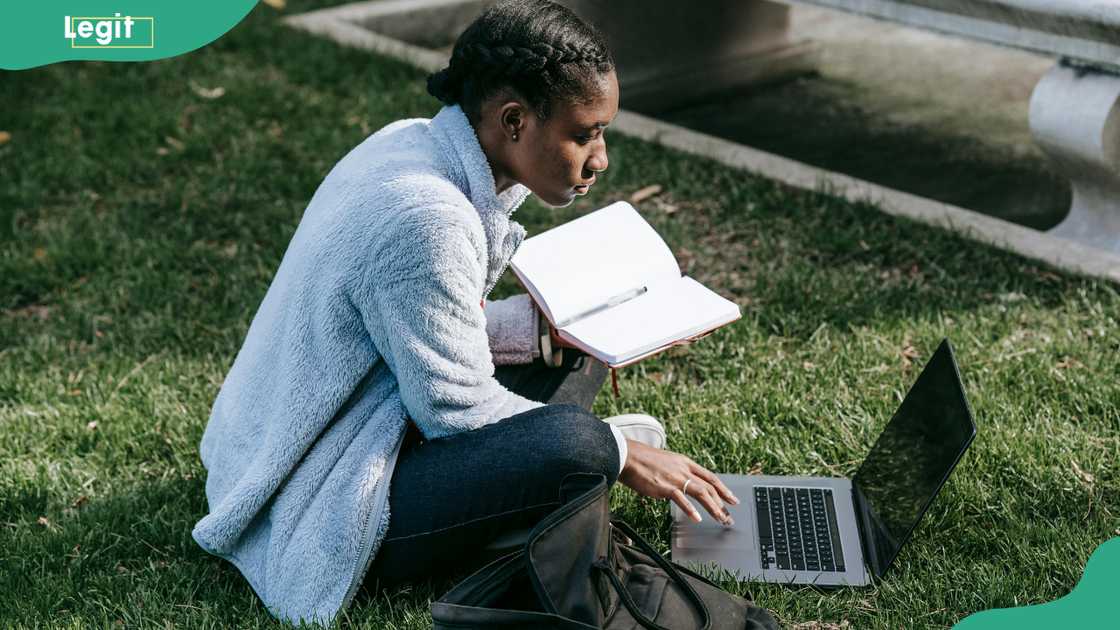 A student studies using a book and a laptop A student studies using a book and a laptop