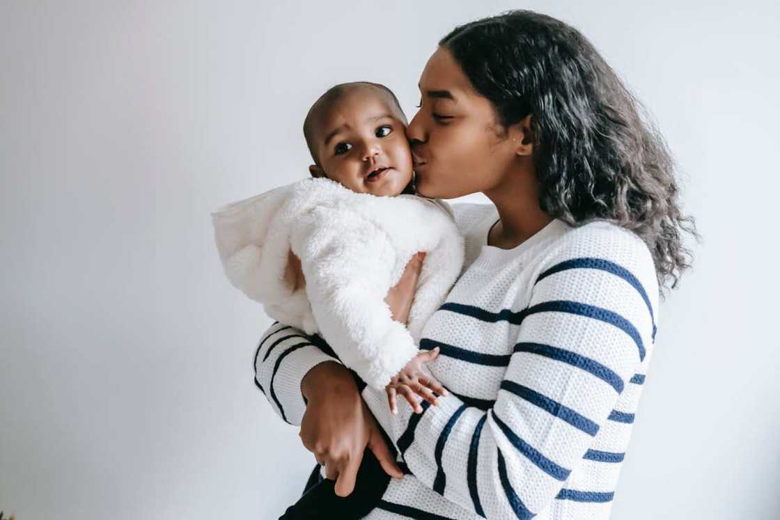 A mother kisses her baby on the cheek