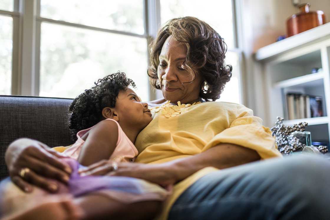 A senior woman cuddling with a young girl A senior woman cuddling with a young girl
