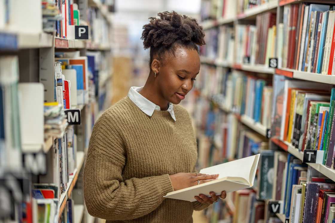 A female student reading a book in the University Library.