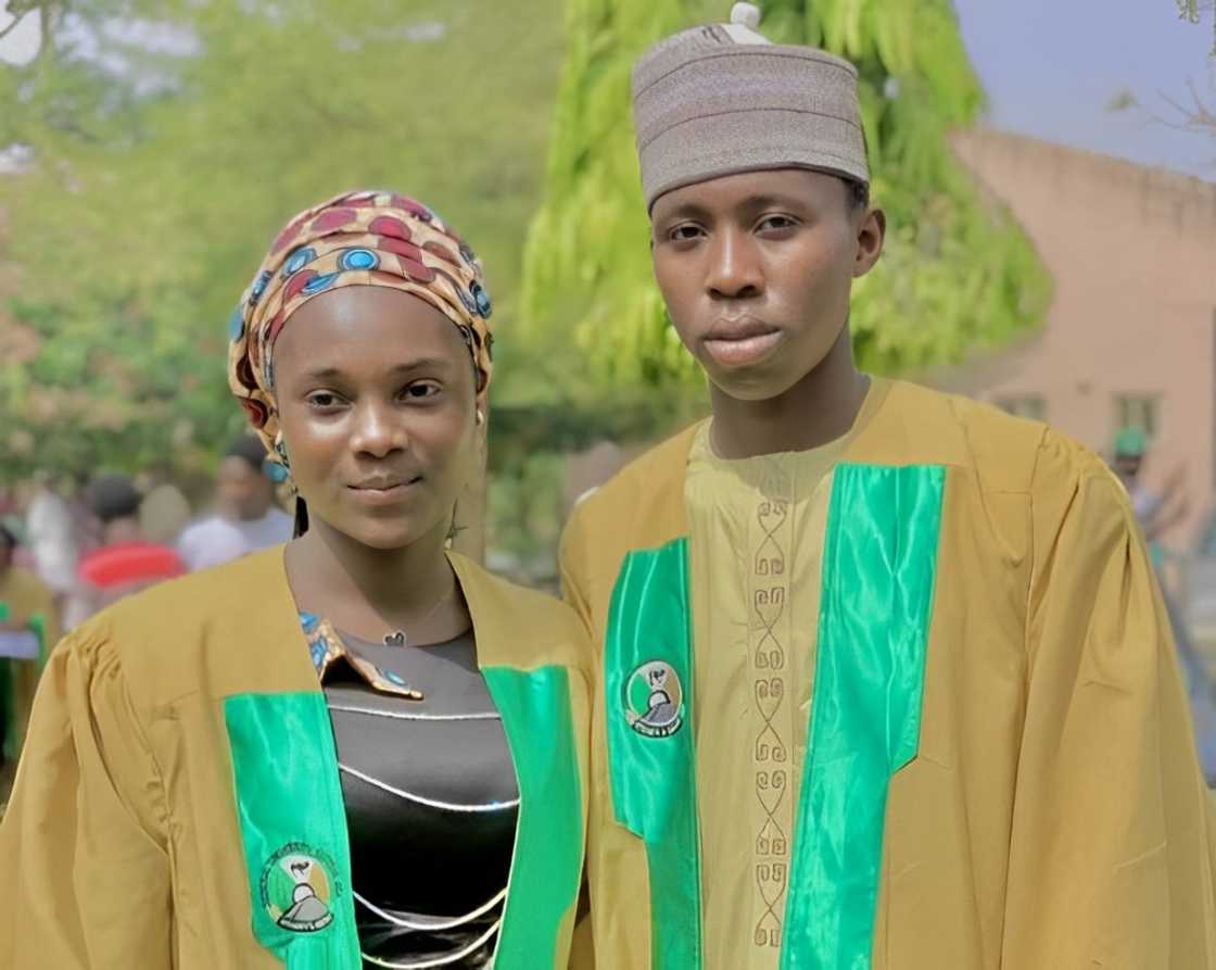 A female and male student posing for a photo in their graduation gown