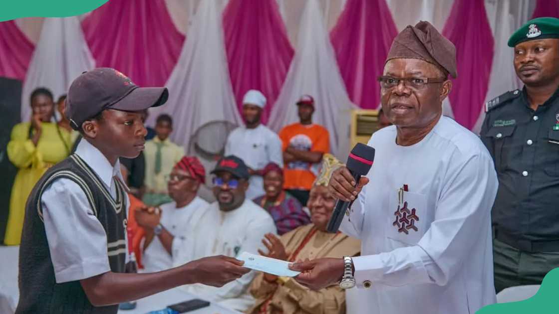 A student receives a cheque from the speaker of the Ondo State House of Assembly A student receives a cheque from the speaker of the Ondo State House of Assembly