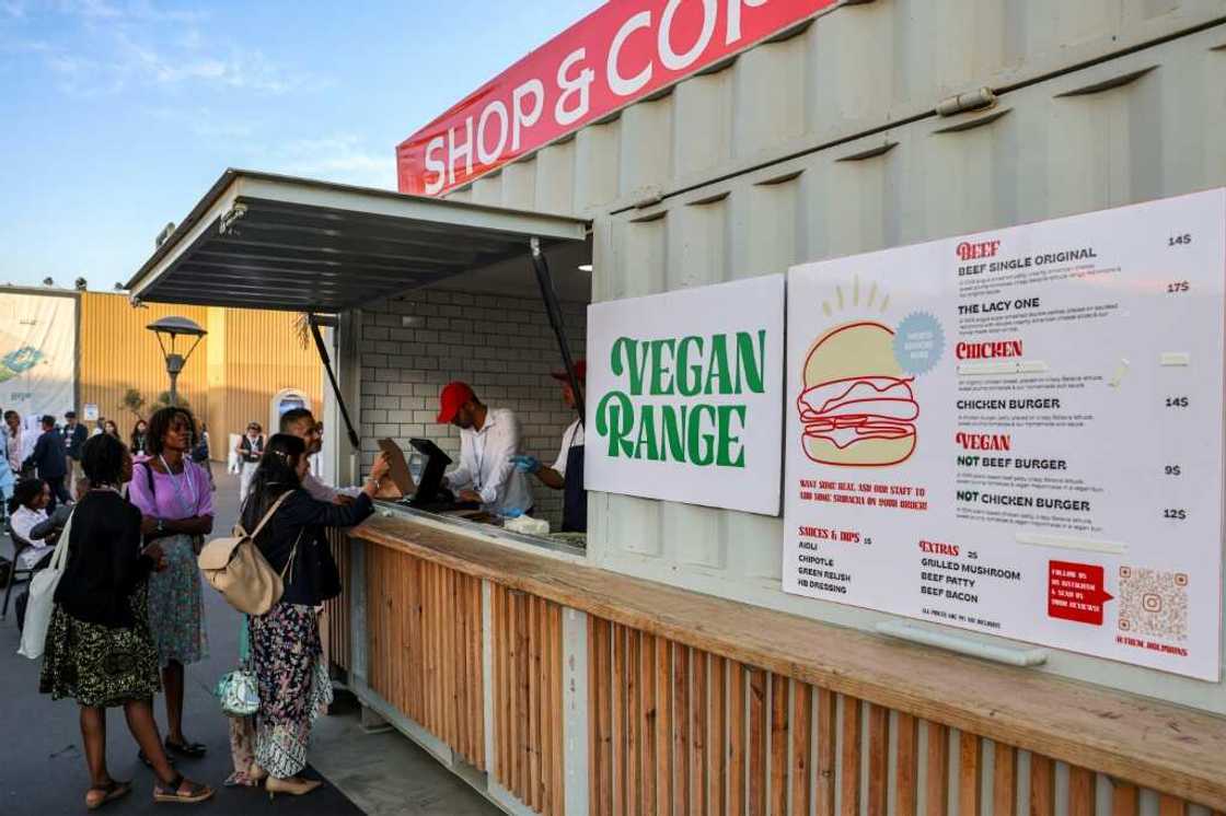 Delegates order from a food stall serving vegan food in addition to beef and chicken at the Sharm el-Sheikh International Convention Centre