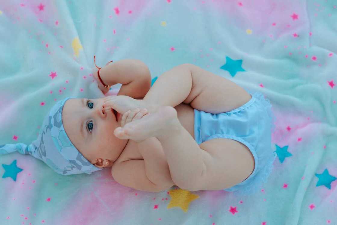 A baby lays on its back on a bed