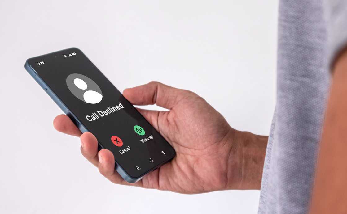 A man holds his mobile phone as a call is declined A man holds his mobile phone as a call is declined