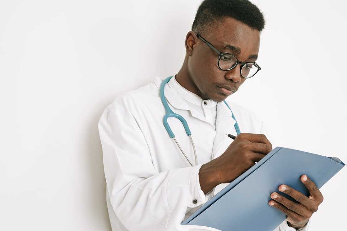 A doctor wearing a stethoscope writing notes on a clipboard.