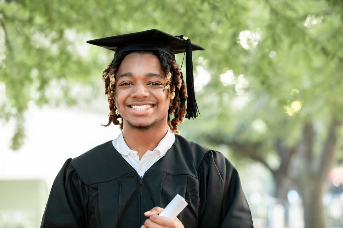 A man smiles for the camera at his graduation. A man smiles for the camera at his graduation.