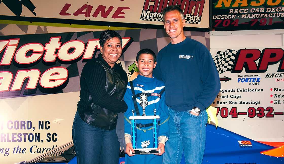 Desiree Lawrence and Darrell Wallace Sr pose with their son as he holds a trophy