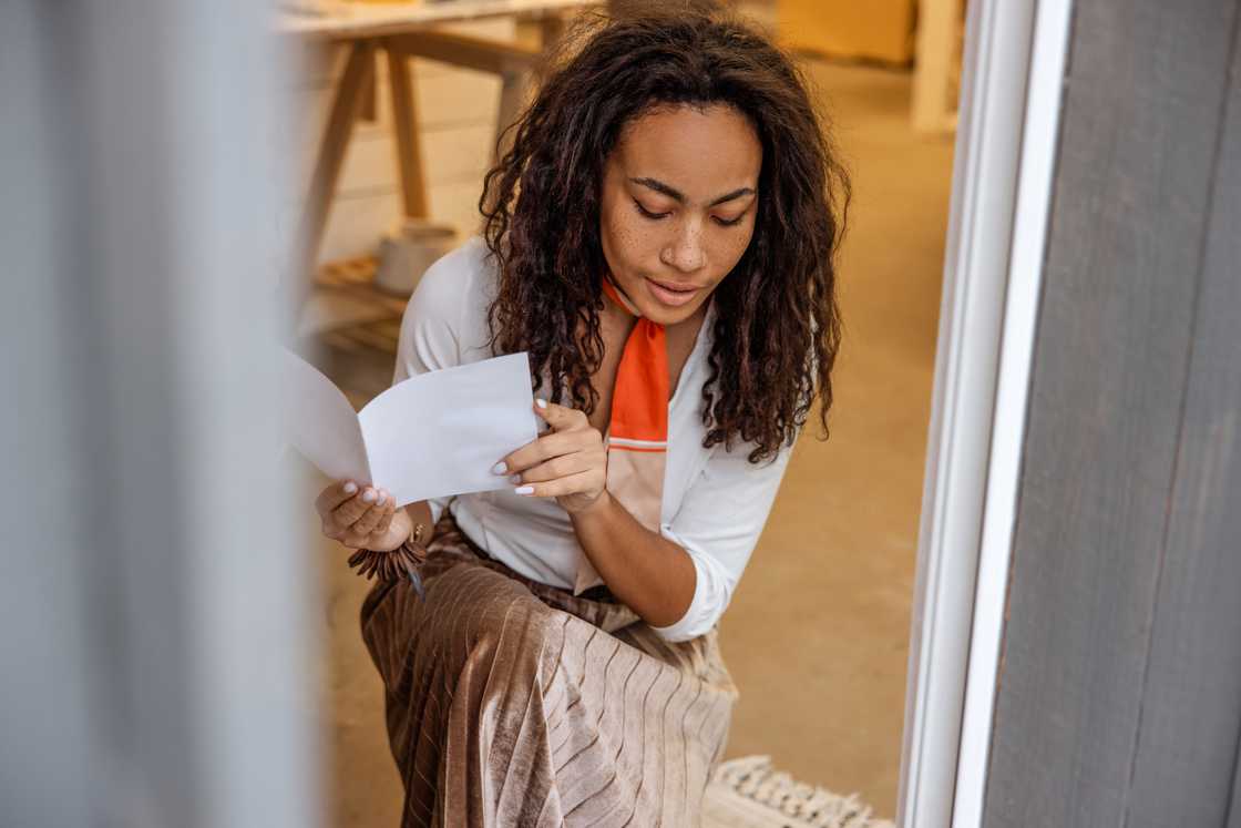 A woman picks up a letter with a puzzled expression.