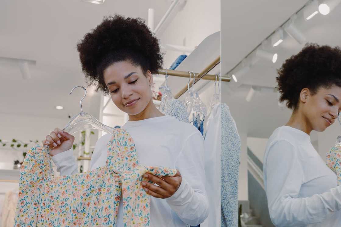 A woman smiles while inspecting a floral dress in a clothing store. A woman smiles while inspecting a floral dress in a clothing store.