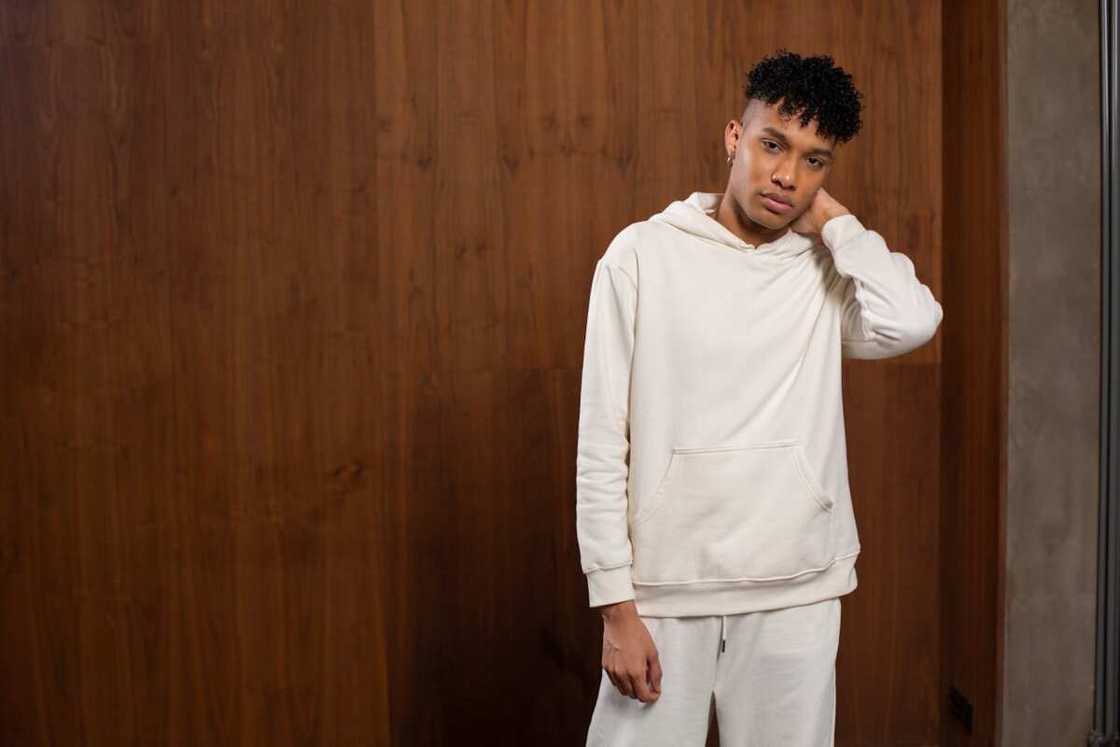 Young man in hoodie staring at someone while touching his neck Young man in hoodie staring at someone while touching his neck