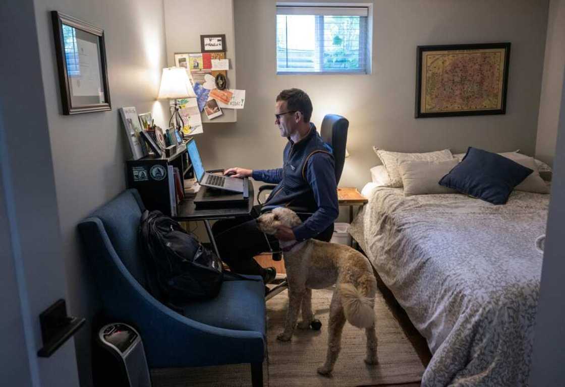 Danny Crouch pets his dog as he sits in his basement working from home in Arlington, Virginia
