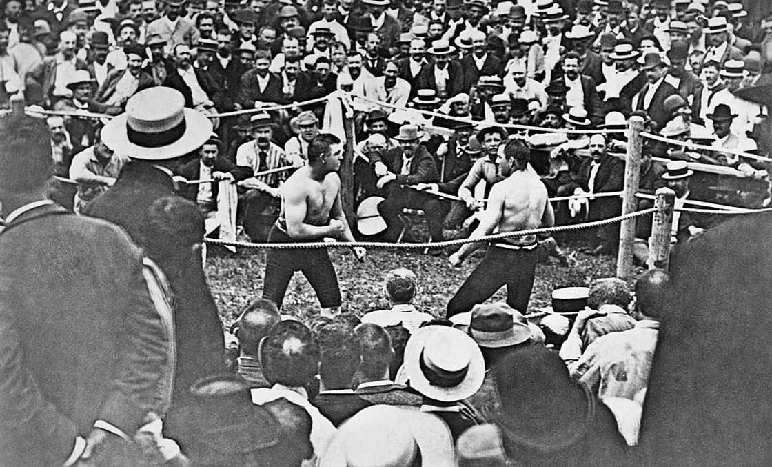 Boxer John L. Sullivan (boxer on left) faces an opponent in front of a large crowd of spectators