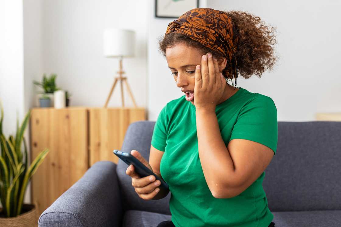 A shocked young woman looking at a mobile phone screen A shocked young woman looking at a mobile phone screen