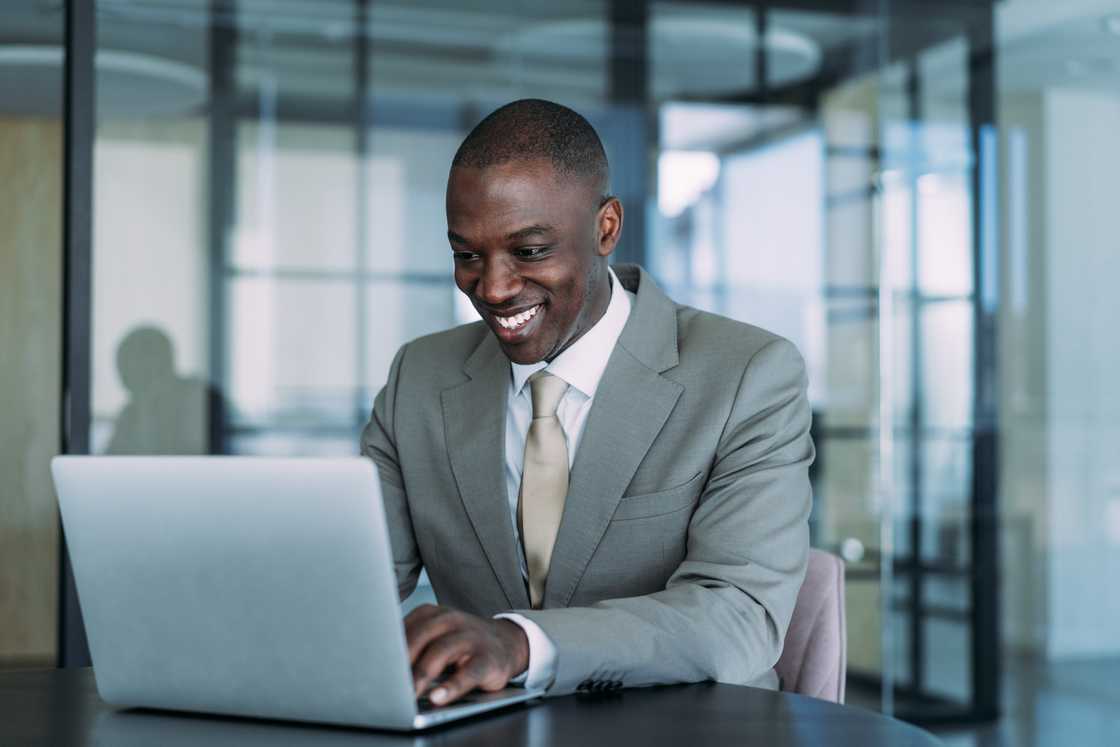 A young man in a modern office working on a laptop.