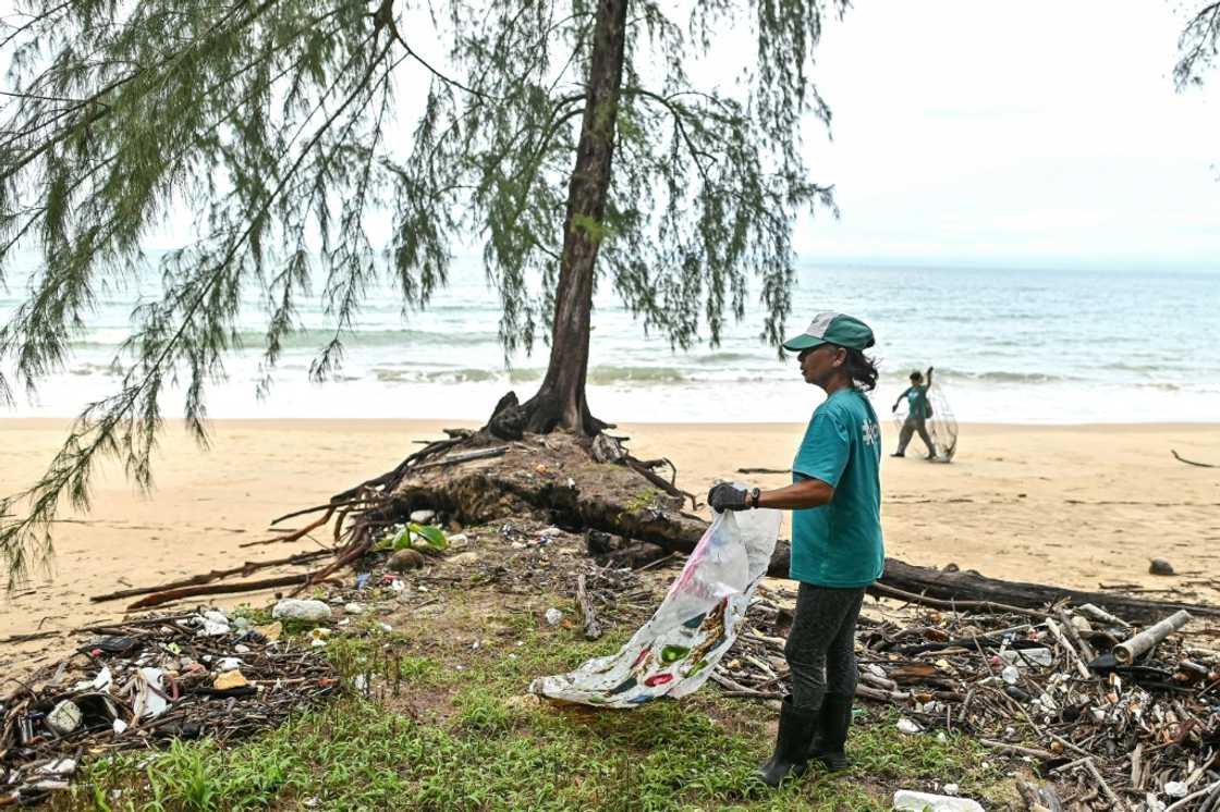 Tide staff member Wiranuch Scimone, 54, collects plastic waste along a beach on Thailand's Koh Chang