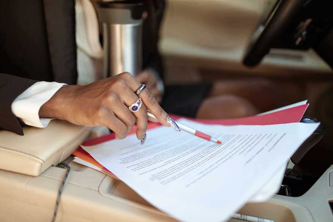 A woman points at a document while reviewing paperwork in a car. A woman points at a document while reviewing paperwork in a car.