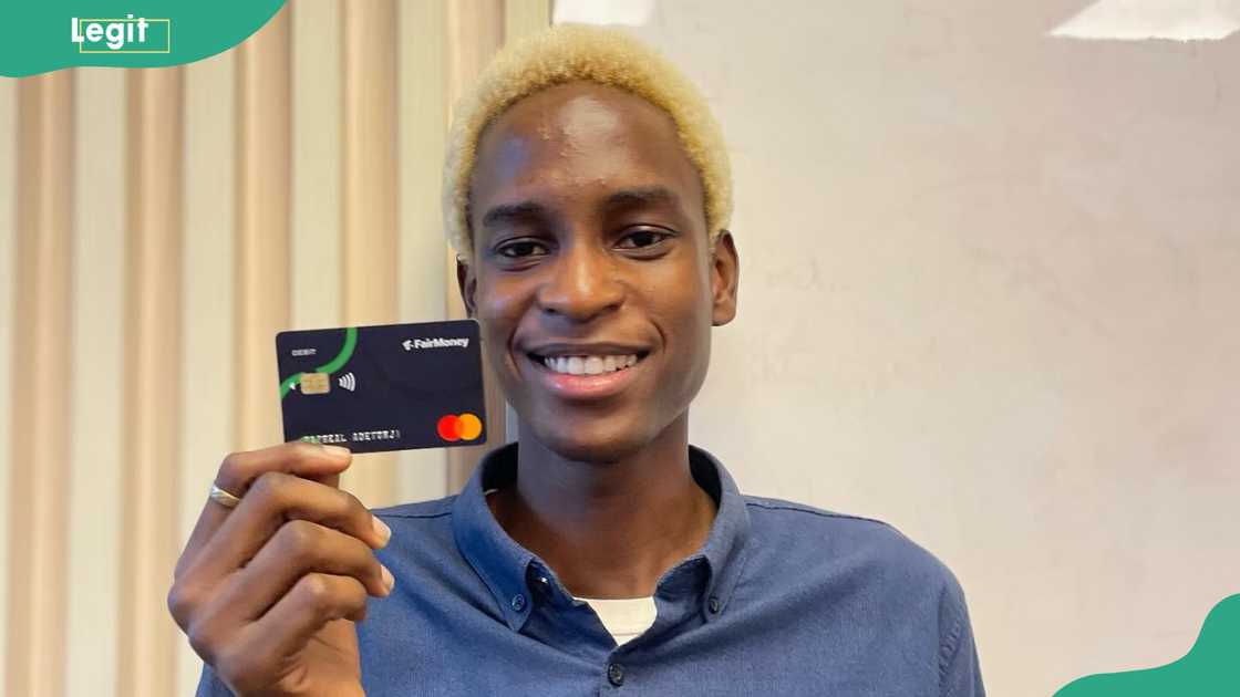 A young man holding up a black FairMoney debit card A young man holding up a black FairMoney debit card