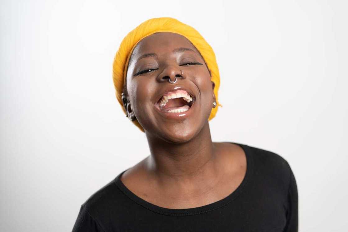 Close-up studio portrait of a happy woman with septum nose piercing laughing at camera