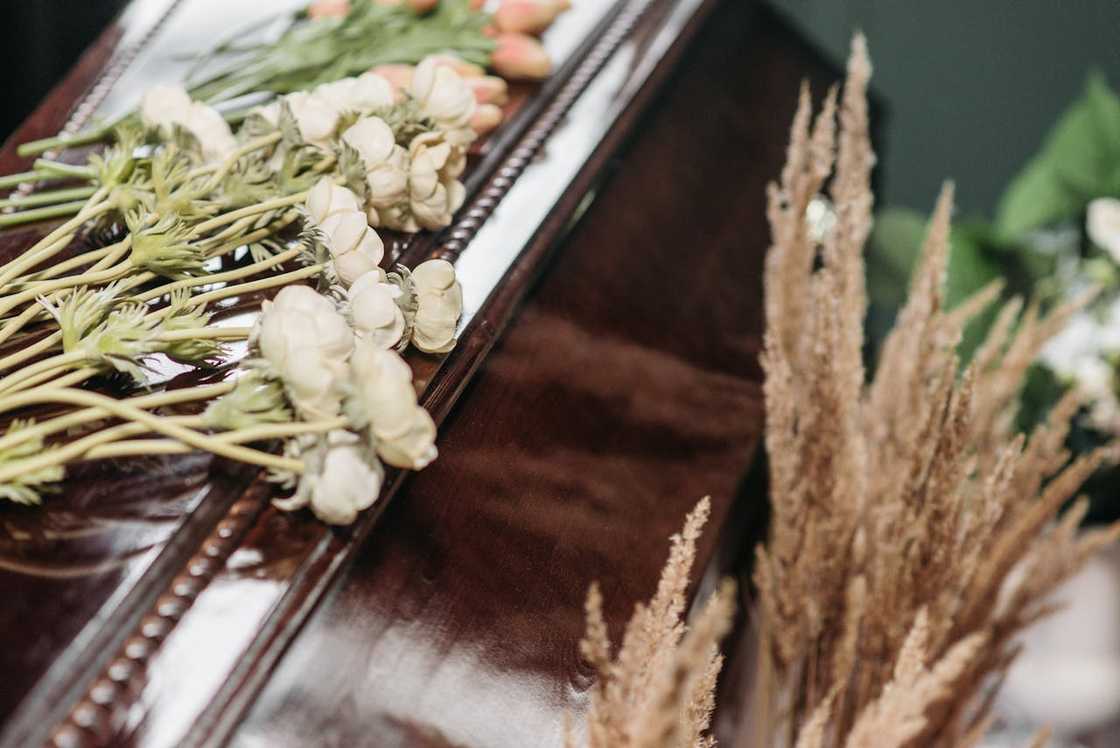 A coffin top covered with white flowers at a funeral. A coffin top covered with white flowers at a funeral.