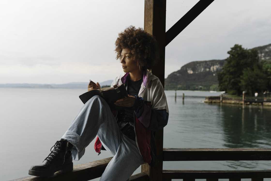 A woman journaling on a dock. A woman journaling on a dock.