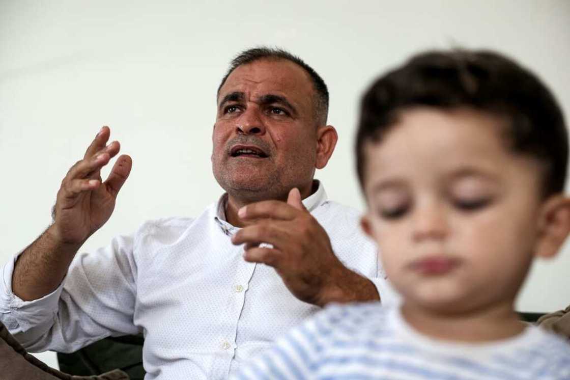 Moatassem Abdel Sater, a 42-year-old former inmate at Sednaya prison, accompanied by his child Othman, gives an interview at his home in Turkey