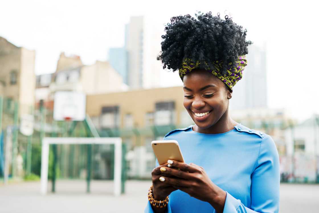 A lady smiling while using a phone A lady smiling while using a phone
