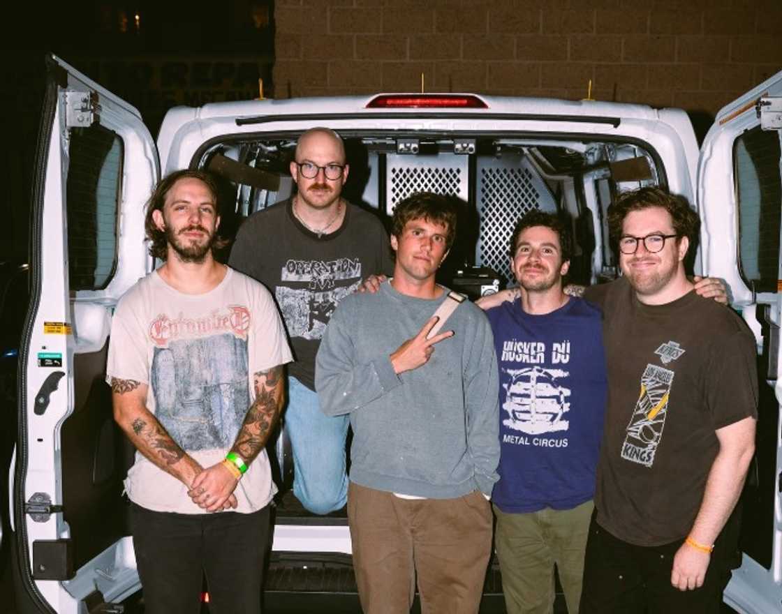 Members of the Cosmic Joke band posing for a photo behind a van Members of the Cosmic Joke band posing for a photo behind a van