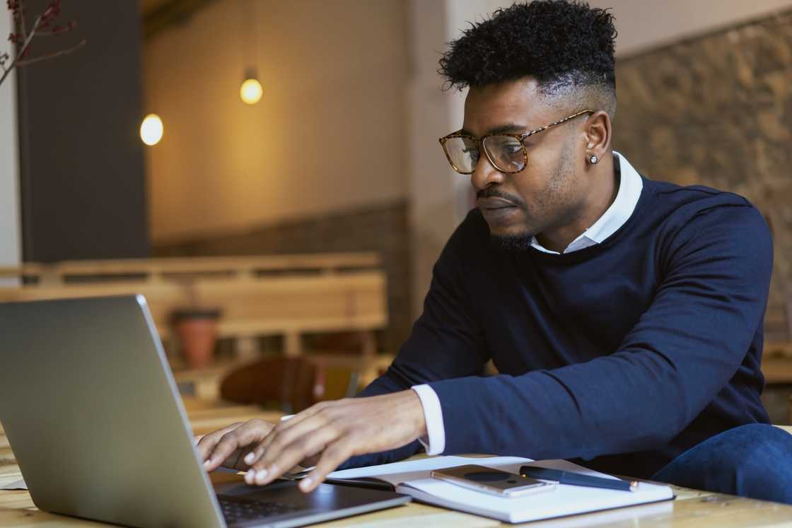 A man works while using a laptop in a cafe setting.