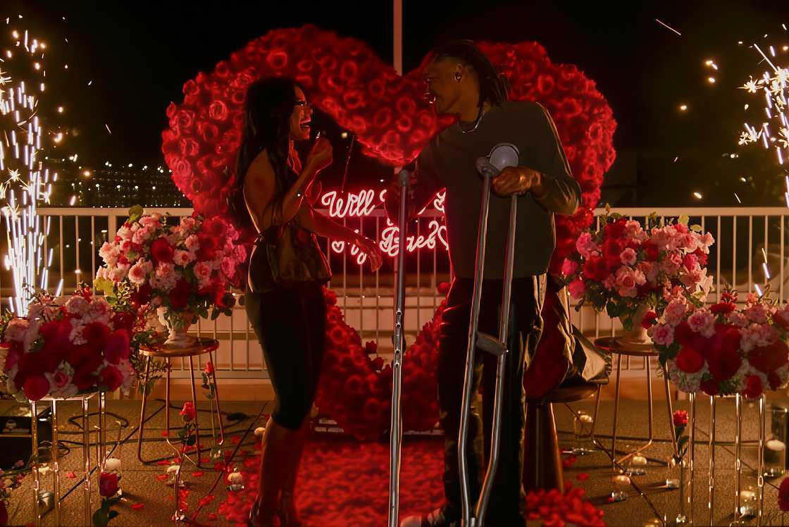 Taylor Williams and Clarke Carraway laugh infront of a flower arrangement