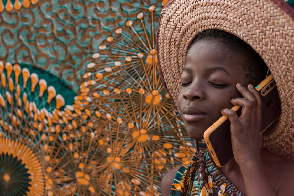 A young boy wearing a hat talking on a smartphone. A young boy wearing a hat talking on a smartphone.