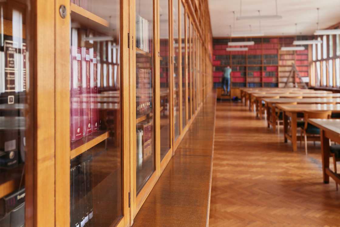 Traditional library reading room with wooden bookshelves and study tables. Traditional library reading room with wooden bookshelves and study tables.