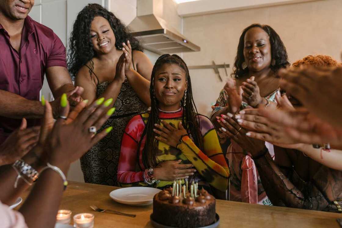 A woman getting emotional as her friends applaud her during a birthday party