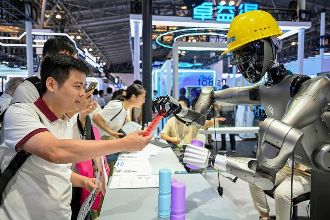 People watch a robot performing tasks at an exhibition during the World AI Conference in Shanghai People watch a robot performing tasks at an exhibition during the World AI Conference in Shanghai