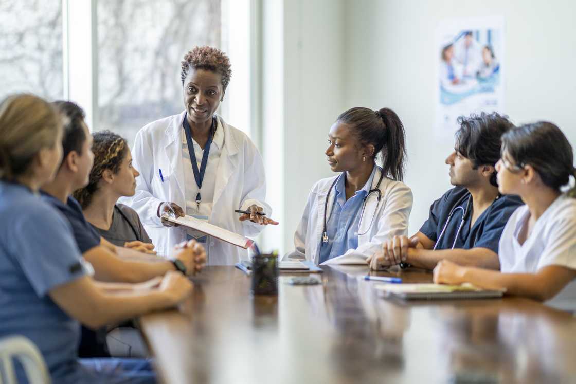 Nursing students sit around a boardroom table Nursing students sit around a boardroom table