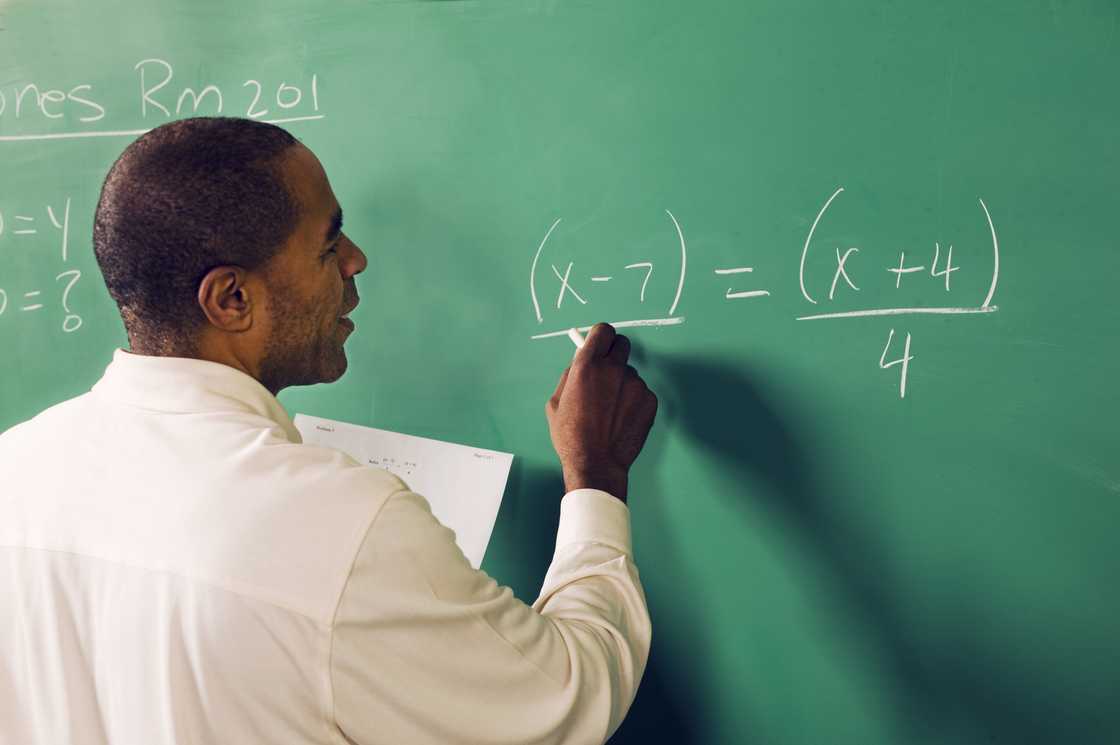 A teacher writing on a green wall