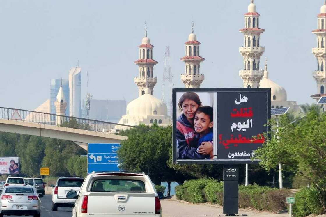 Cars drive past a billboard in Kuwait City showing Palestinian children and the slogan: "Have you killed a Palestinian today? #boycott"