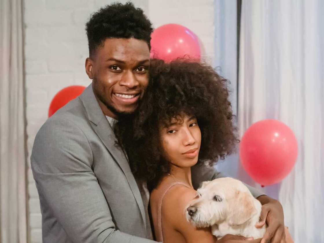 A couple holding a cute dog while standing in decorated room A couple holding a cute dog while standing in decorated room