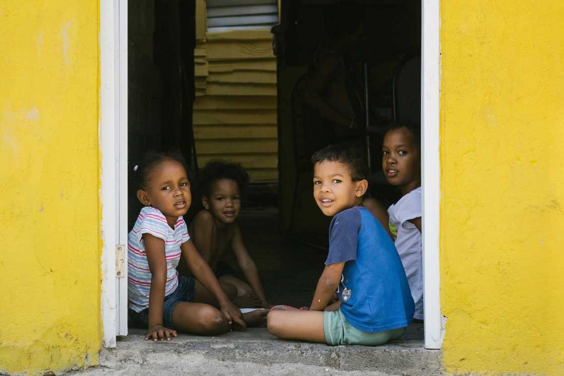 Children sitting on a doorway smiling Children sitting on a doorway smiling