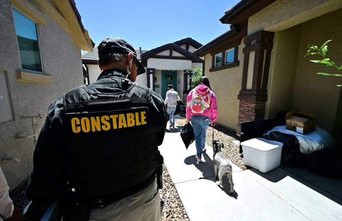 Lennie McCloskey, Constable of Manistee Justice Precint in Maricopa County watches as a family who has just been evicted carry out their belongings on April 15, 2024 in Phoenix, Arizona Lennie McCloskey, Constable of Manistee Justice Precint in Maricopa County watches as a family who has just been evicted carry out their belongings on April 15, 2024 in Phoenix, Arizona