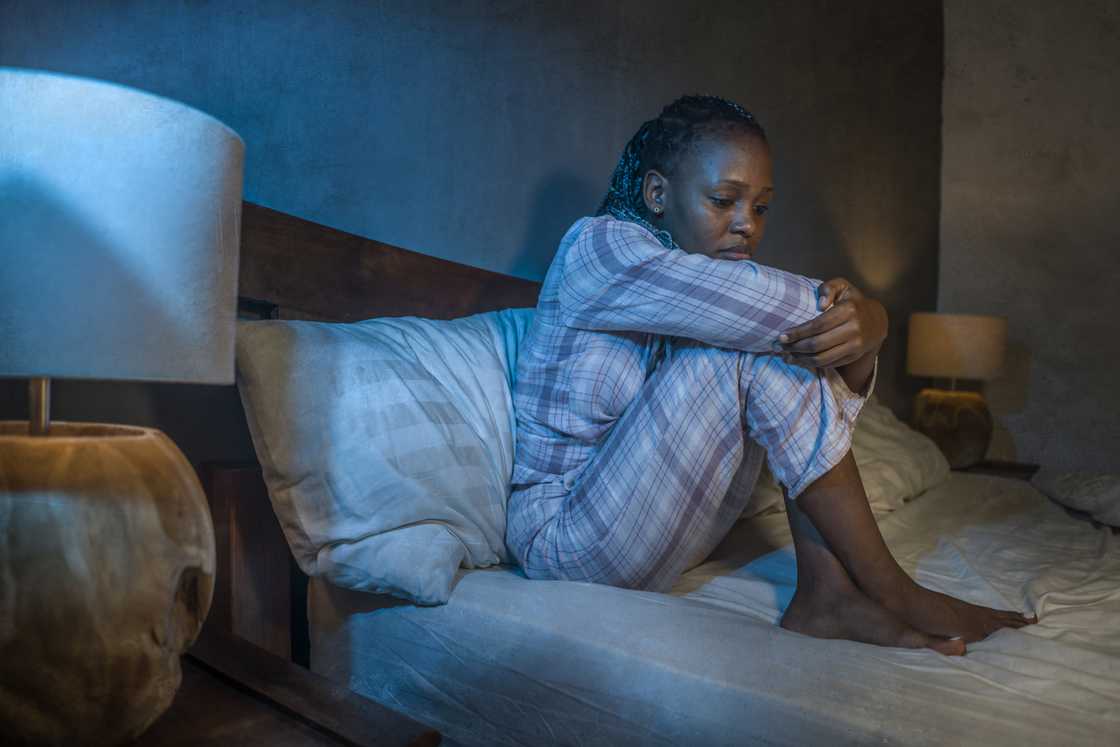 A young, sad and depressed woman sitting on bed